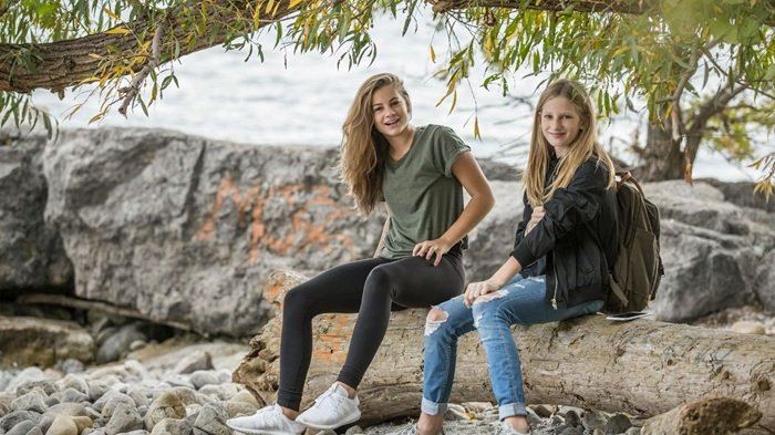 2 teen girls Sitting on Rock during Daytime
